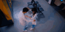 a man and a woman in lab coats are dancing in a waiting room with a sign that says lab