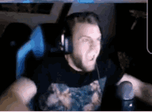 a man wearing headphones and a floral shirt is sitting in a chair in front of a microphone .