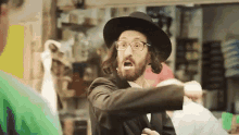 a man with a beard wearing glasses and a hat is pointing at someone