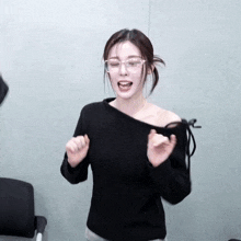 a woman wearing glasses and a black off the shoulder top is dancing