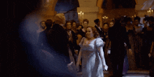 a woman in a white dress is standing in front of a crowd
