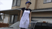 a woman wearing a white apron and a blue hat stands in front of a vehicle