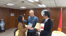a man in a suit is holding a book in front of a wall with chinese writing on it