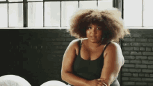 a woman with a big afro is sitting in front of a window .