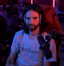 a man with long hair and a beard wearing a british connection shirt