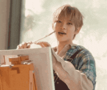 a young man is painting on a canvas on an easel .