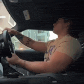a man is driving a car with a tattoo on his arm that says m.