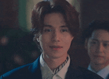 a man in a suit and tie is smiling with another man in a suit behind him