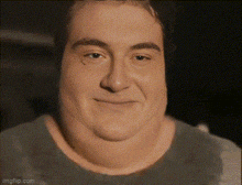 a close up of a man 's face with a very large neck and a smile on his face .