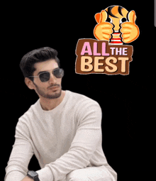 a man wearing sunglasses sits in front of a sign that says " all the best "