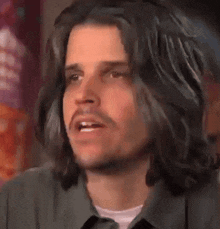 a man with long black hair and a beard is looking at the camera