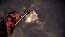 a man in a red suit is holding a spear with the letter t on it