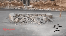 a pile of rocks on the ground with a sad face drawn on it