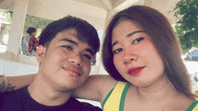 a man and a woman are posing for a picture and the woman is wearing a yellow tank top