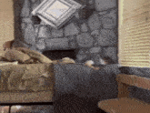 a man laying on a bed reading a book in front of a stone fireplace .