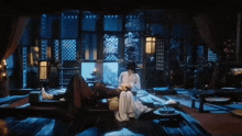a man and woman are laying on a bed in a room with a lot of windows .