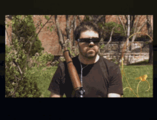 a man wearing sunglasses is holding a rifle on his shoulder