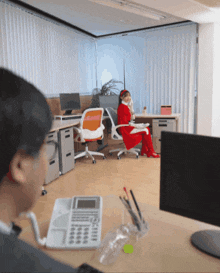 a woman in a santa suit is sitting at a desk in an office