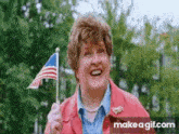 an older woman in a red jacket is holding an american flag and smiling .
