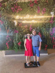 a man and woman standing in front of a wall that says it is all a dream
