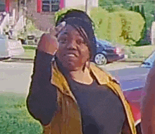a woman is giving the middle finger while standing in front of a car .