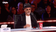 a man wearing a hat is sitting at a table with a tim hortons cup