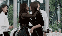 two women are kissing each other while standing next to each other .