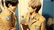 two people in military uniforms are looking at each other and one has an x on his chest