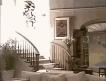 a living room with a couch , stairs , and a vase of flowers .