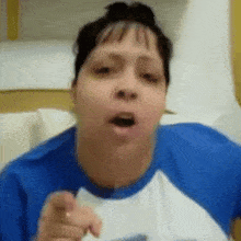 a woman in a blue shirt is pointing her finger