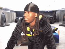a man with dreadlocks is wearing a headband and a black jacket