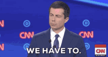 a man in a suit and tie says we have to in front of a cnn logo