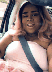 a woman with pink hair is sitting in a car with a seat belt around her waist