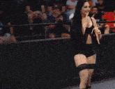 a woman in a black top and shorts is walking on a stage