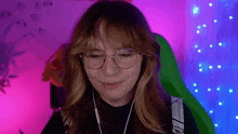 a woman wearing glasses and headphones is smiling in front of a green chair