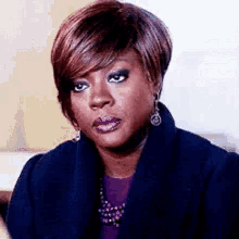 a woman is making a funny face while wearing a purple shirt and earrings .