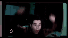 a young man is making a funny face while sitting in front of a computer screen .
