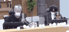 two men wearing masks and headphones are sitting in front of microphones in a studio .