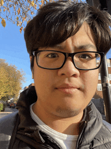 a young man wearing glasses and a black jacket