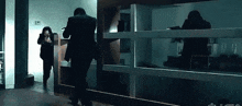 a man in a suit is running in a dark room with a gun in his hand