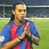 a soccer player in a blue and red jersey is clapping his hands
