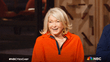 a woman is smiling in front of a sign that says nbc on it