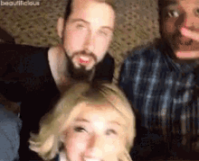 two men and a woman are posing for a picture and the woman is smiling for the camera .