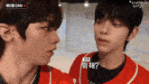 two boys are looking at each other and one has a red shirt on that says cam
