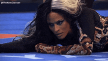 a woman in a snakeskin outfit is laying on the ground