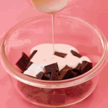 a glass bowl filled with chocolate and whipped cream on a pink surface