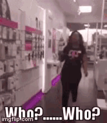 a woman is walking down a hallway in a store with the words `` who ? '' written on the bottom .
