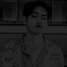 a black and white photo of a man wearing a necklace