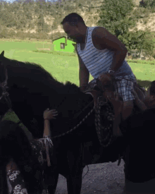 a man in a tank top is riding a black horse