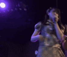a woman is singing into a microphone in a dark room